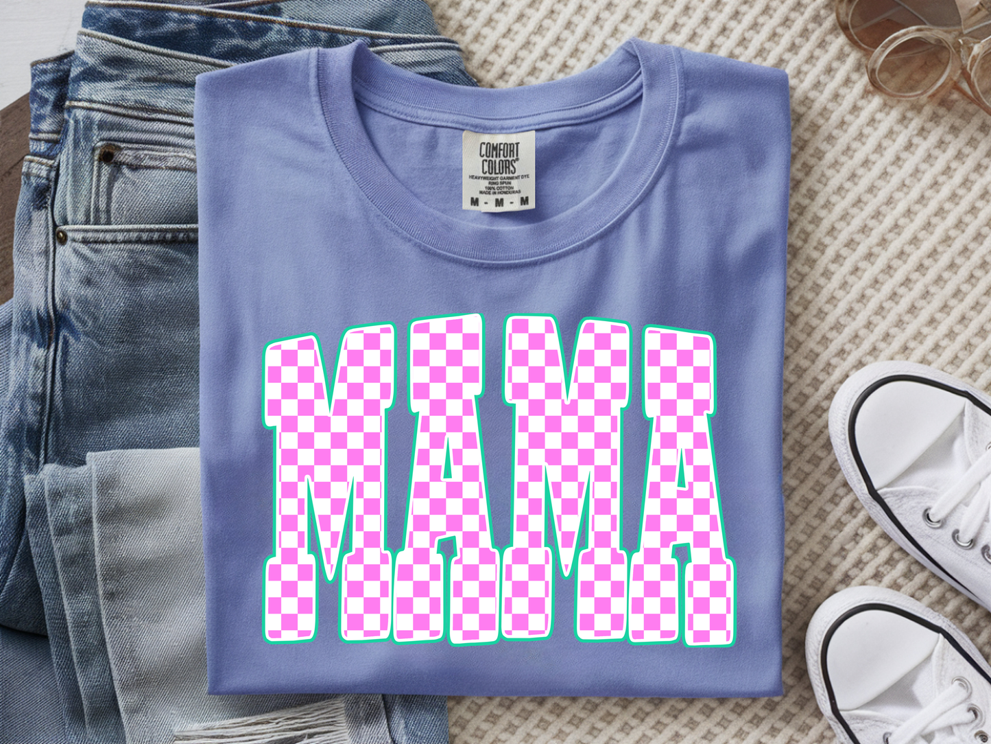 washed denim  t-shirt with 'MAMA' in pink checkered letters on a textured surface with jeans and sneakers.