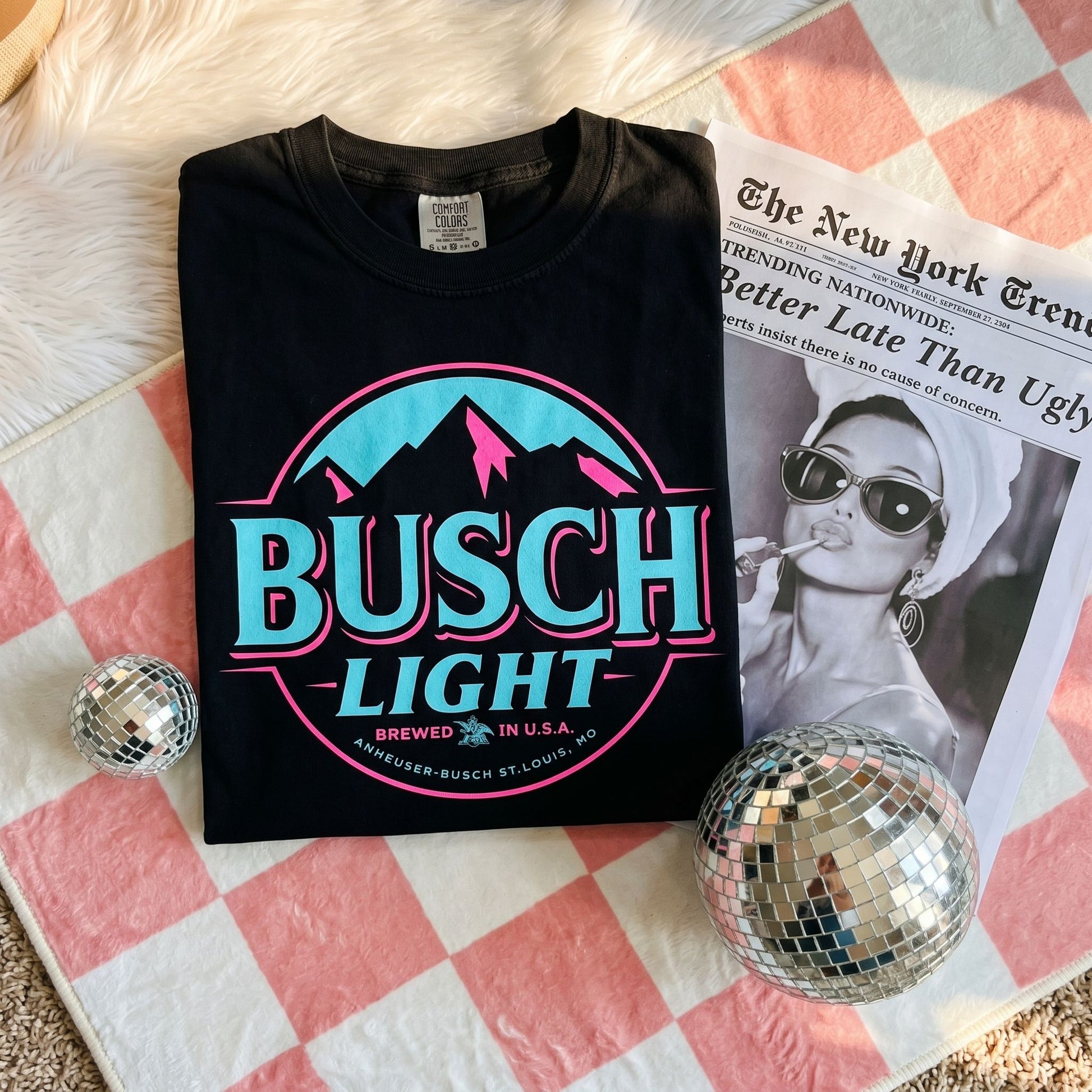 Casual scene featuring Busch Light Neon graphic tee on a person in a warm-lit living room environment.