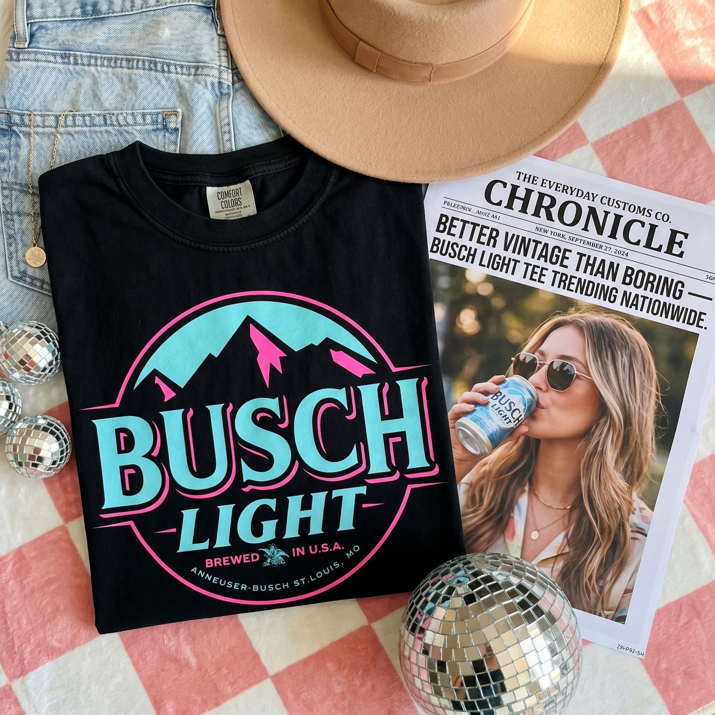Friends relaxing on a sofa, showcasing Busch Light Neon Vintage Print Graphic Tees in a cozy environment.