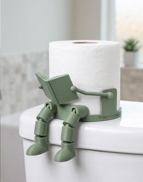 Green 3D-printed articulated reading-man robot toilet paper holder gripping a book on a toilet tank, bathroom decor.