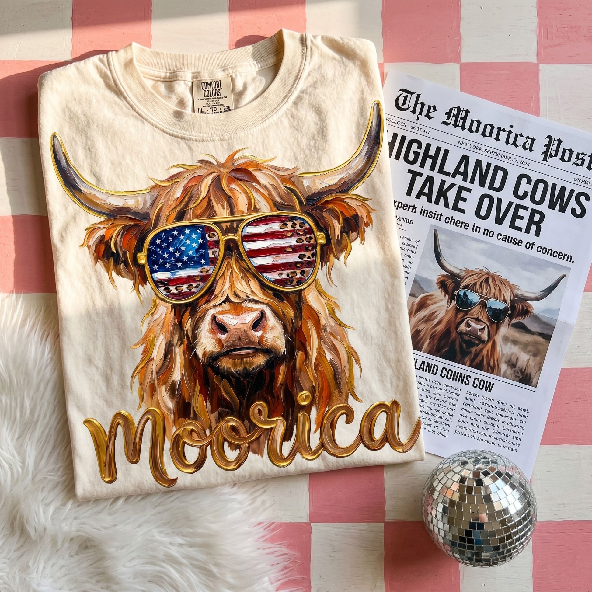 Close-up of the Highland Cow graphic tee highlighting the full-color print and vibrant design in a warm, casual setting.