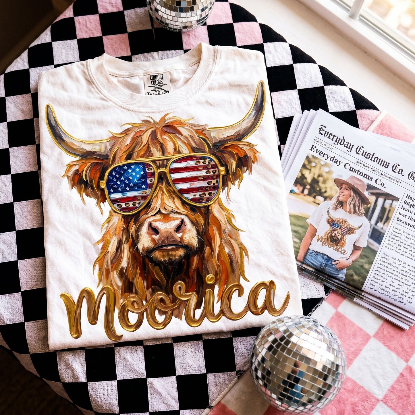 Person wearing the Comfort Colors Highland Cow graphic tee, relaxing in a cozy living space with natural lighting.